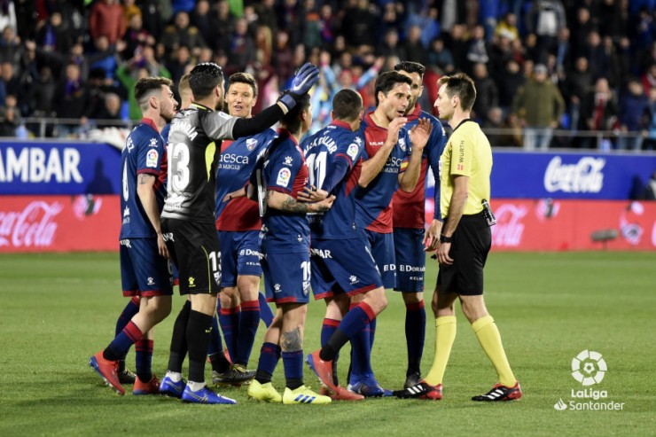 Jugadores del Huesca protestan una decisión a  De Burgos Bengoetxea durante el duelo ante el Sevilla.