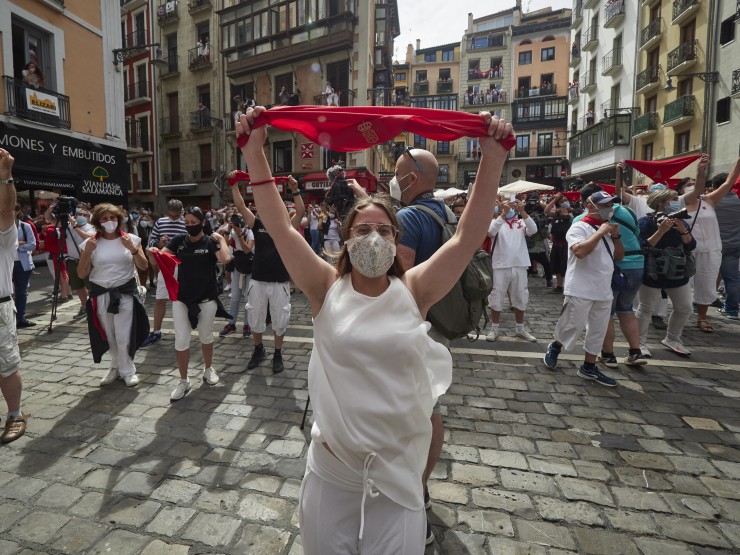 Varias personas alzan un pañuelo rojo en las inmediaciones de la Plaza del Consistorio en el momento en el que de celebrarse los Sanfermines 2020 (EP).