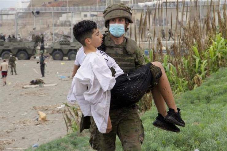 Un soldado del Ejército de Tierra ayuda a un inmigrante que ha logrado cruzar uno de los espigones fronterizos de Ceuta.