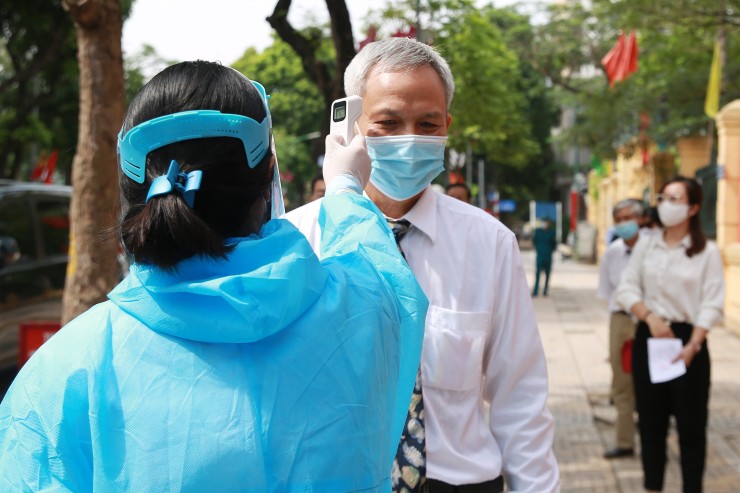 Una sanitaria vietnamita toma la temperatura a un ciudadano.