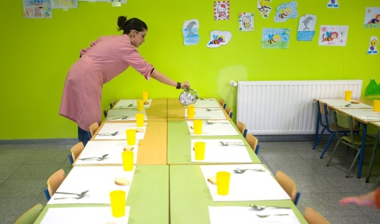 Una cuidadora del comedor escolar prepara la mesa para los alumnos (EP).
