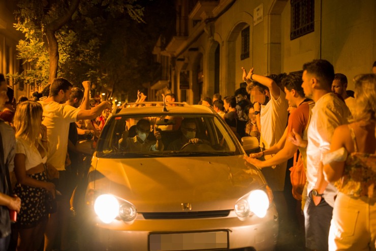 Decenas de personas rodean a un vehículo que circula por una calle del barrio de Gracia en plenas fiestas (EP).