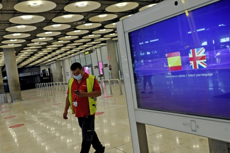 Un operario de Iberia pasa al lado de un monitor con las banderas de España y Reino Unido en la T1 del Aeropuerto de Madrid-Barajas (EP).
