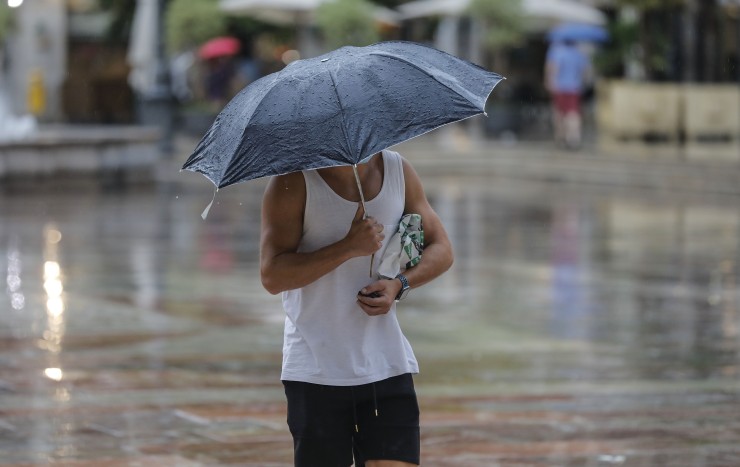 Un hombre se protege de la lluvia con un paraguas (EP).