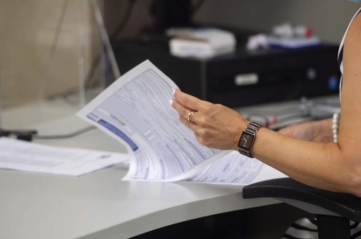 Una empleada hojea varias hojas en su puesto de trabajo de la Oficina de Hacienda (EP).