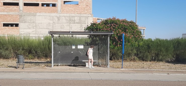 Una mujer espera el autobús de Plaza en una marquesina.