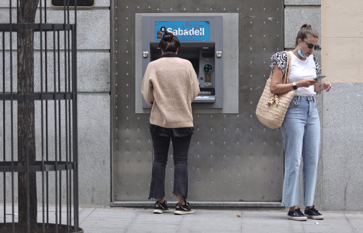 Dos personas junto a un cajero del Banco Sabadell. (EP)
