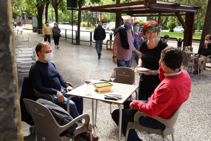 Dos hombres conversan con una camarera en el centro de Zaragoza.