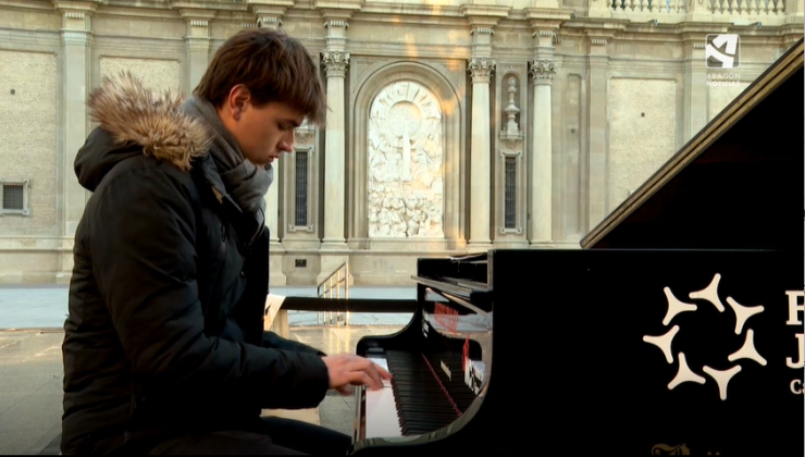 Un joven toca uno de los pianos ubicados en la plaza del Pilar de Zaragoza.