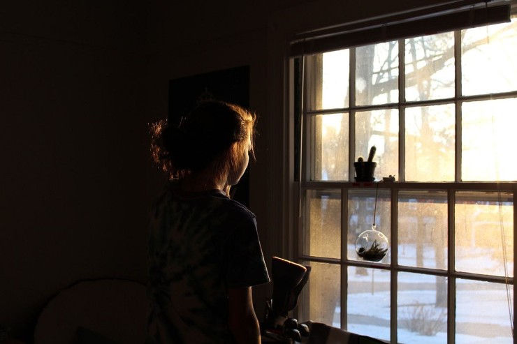 Una niña mira por la ventana.