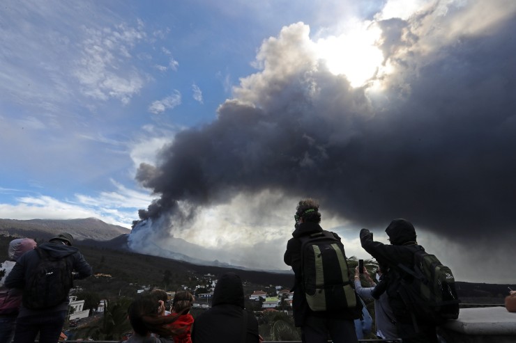 Varios turistas contemplan la erupción volcánica desde la plaza de Tajuya (La Palma). (Foto: EFE)