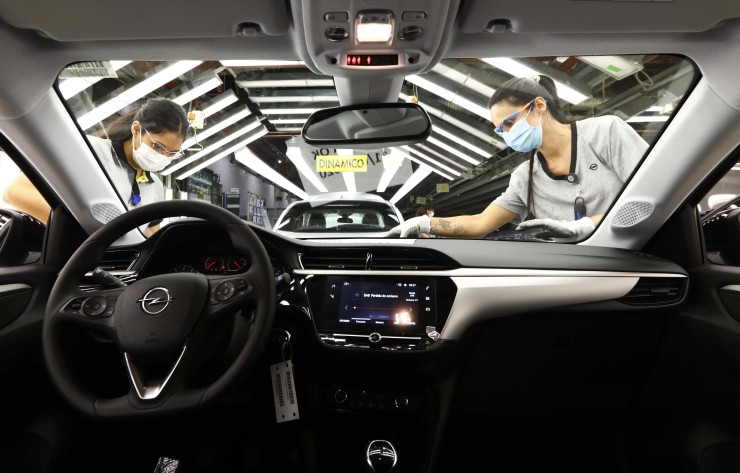 Vista del interior de un coche mientras dos personas desarrollan su trabajo en la planta de Figueruelas. / Foto: EP