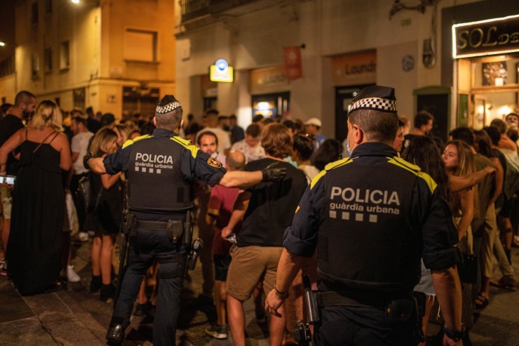 Agentes de la Guardia Urbana de Barcelona se dirigen a la multitud para controlar aglomeraciones en las fiestas del barrio de Gràcia. / Foto: EP