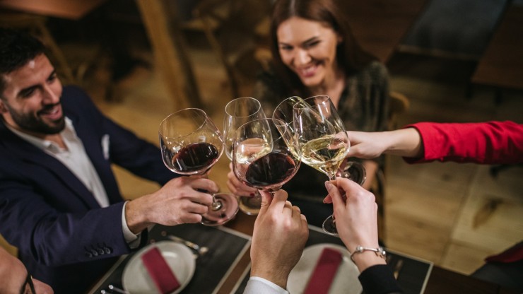 Un grupo de cuatro personas brindan con copas de vino. / CANVA