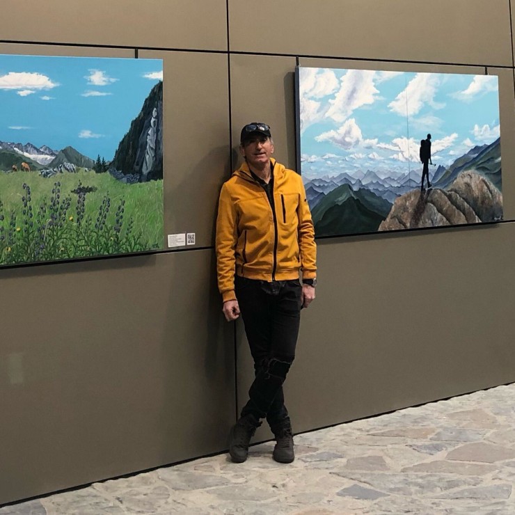 El artista Jesús Bernat posa junto a varias de sus cuadros en los que refleja la belleza de los paisajes del Pirineo aragonés. / Jesús Bernat