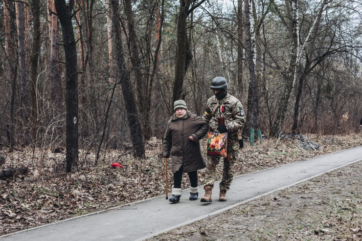 Un soldado ayuda a camina a una anciana en Irpin (Ucrania).