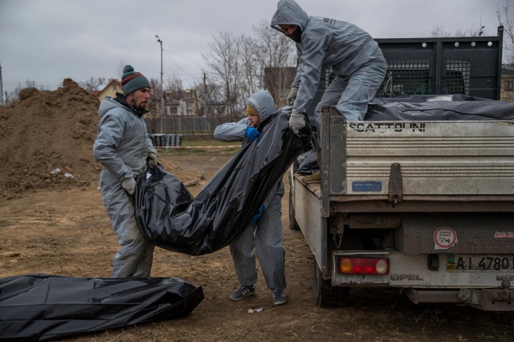 Autoridades forenses recogen cadáveres envueltos en plásticos para su traslado a la morgue en Bucha (Ucrania). / Foto: EFE.