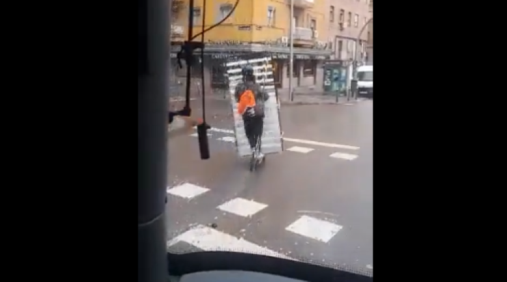 Imagen del vídeo en el que un conductor de patinete transporta un somier.