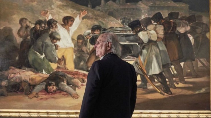 Carlos Saura posa frente a la obra de Francisco de Goya 'Los fusilamientos del 3 de mayo'.