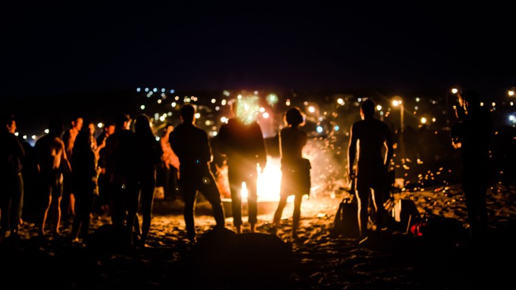 Un grupo de personas celebran la noche de San Juan alrededor de una hoguera.