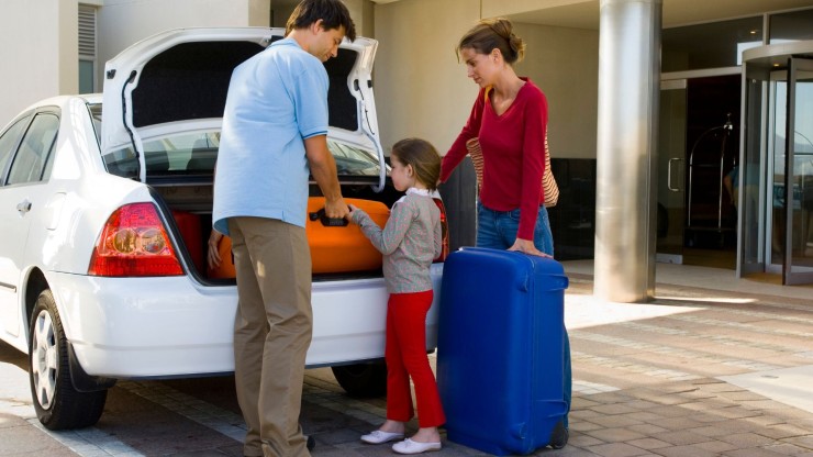 Una familia introduciendo las maletas en el coche antes de irse de vacaciones.
