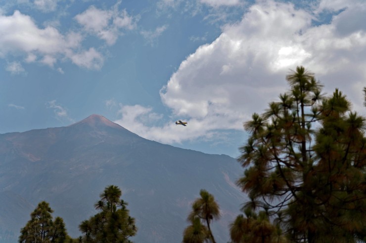 Un avión pasa junto al pico de El Teide en uno de sus viajes a la costa para abastecerse de agua durante las labores de extinción del incendio. / EFE.