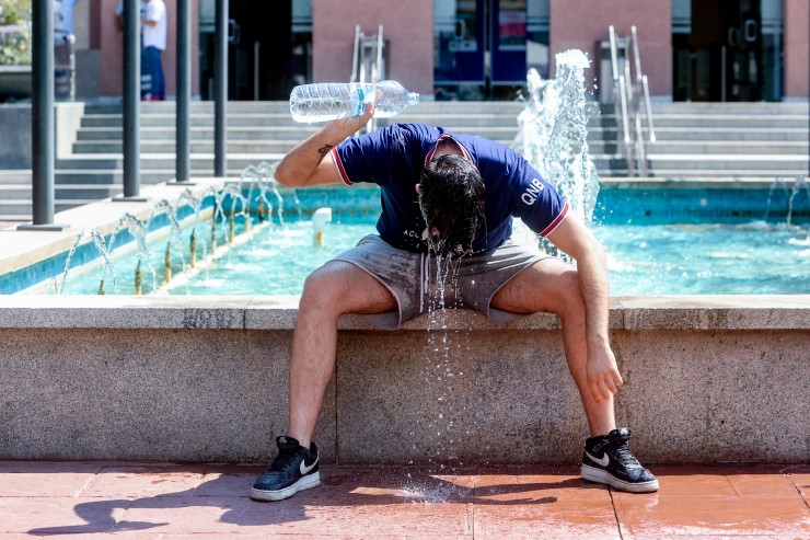 Un joven se tira una botella de agua por encima para combatir la segunda ola de calor del verano. / Europa Press