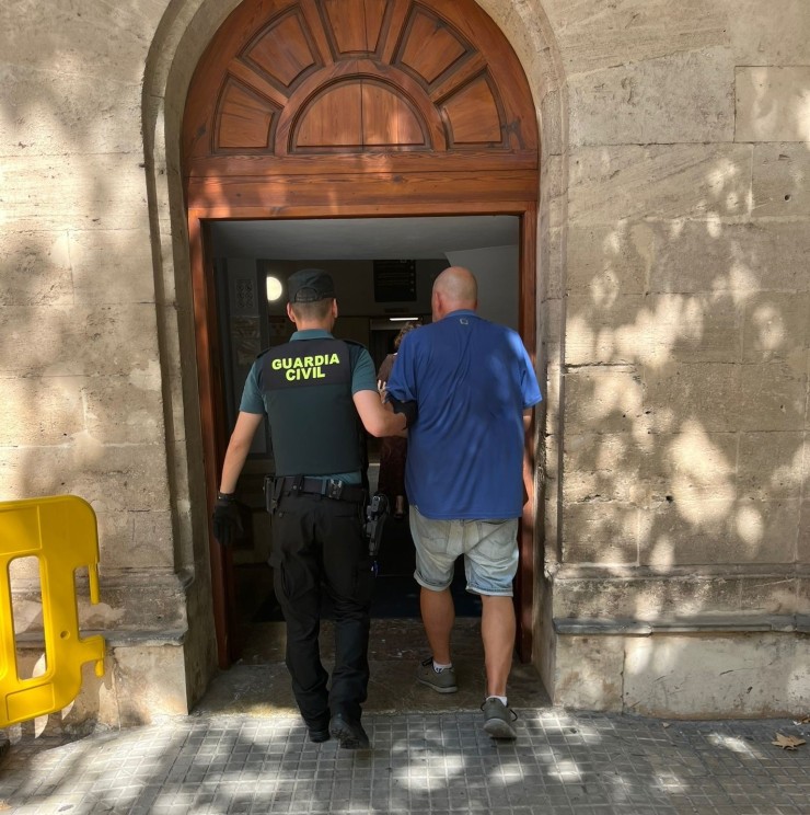Un agente de la Guardia Civil con el presunto autor de los incendios en Calviá, Mallorca. (Europa Press)