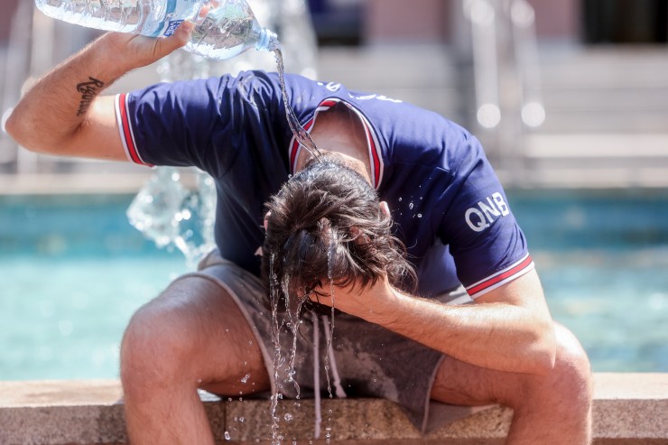 Un joven se tira una botella de agua por encima para combatir el calor. / Europa Press