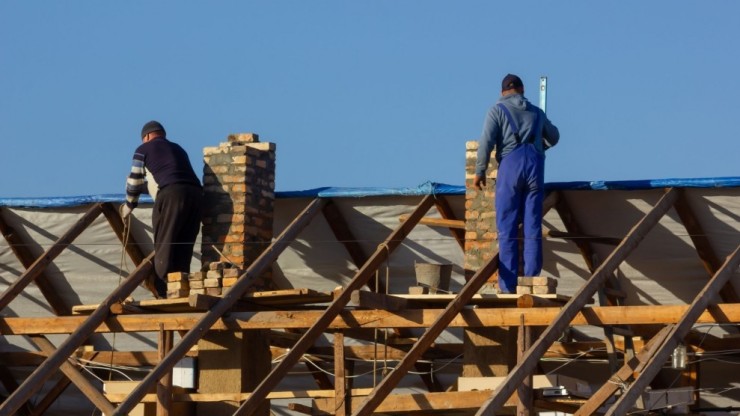 Dos personas realizan una obra en el tejado de una casa.