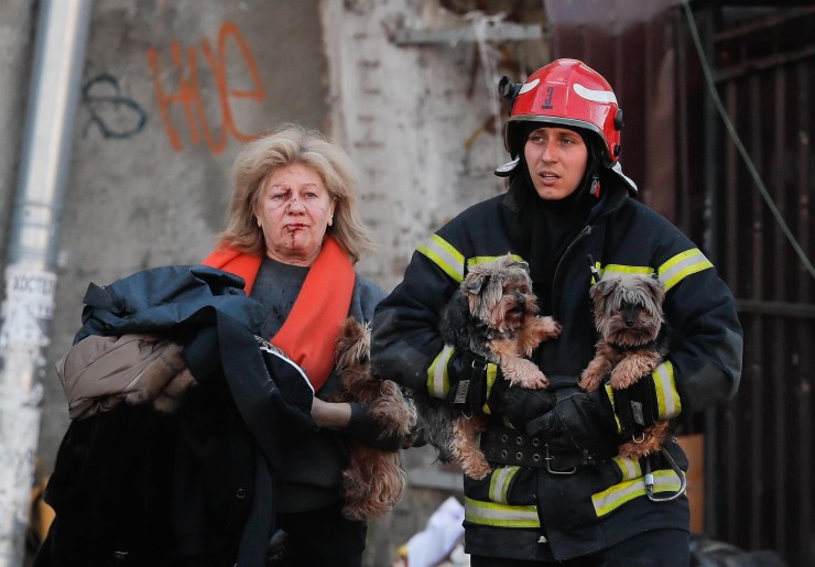 Un rescatista ucraniano ayuda este lunes a una mujer herida y a sus perros tras un bombardeo en el centro de Kiev (Ucrania). (EFE/ Sergey Dolzhenko).