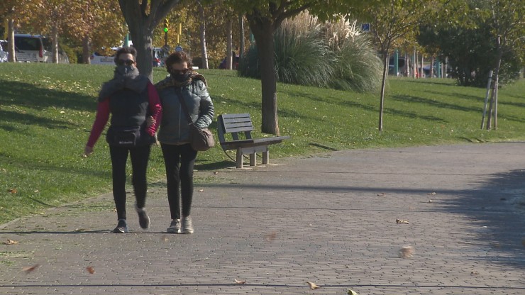 Dos mujeres se protegen del fuerte viento en el paseo de la Ribera de Zaragoza.