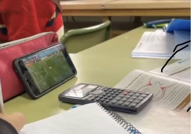 Un alumno sigue un partido del Mundial desde su móvil mientras está en clase.