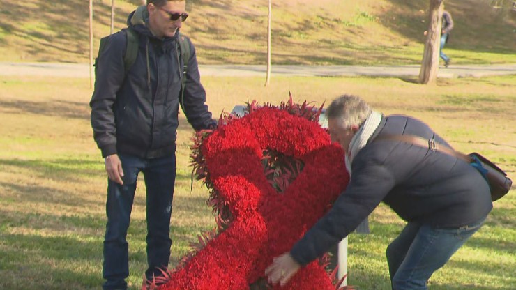 Colocación de un lazo rojo, símbolo de la lucha contra el sida, en el acto de Parque Bruil.