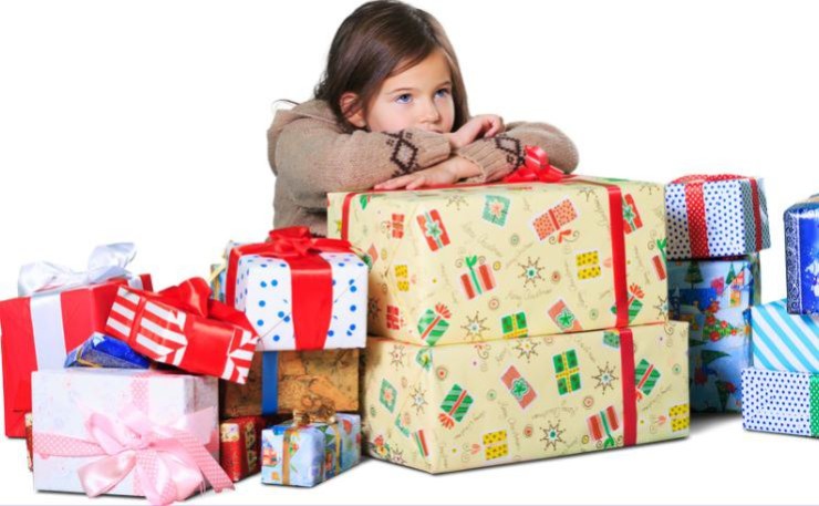 Una niña apoyada en paquetes de regalos. / Canva.