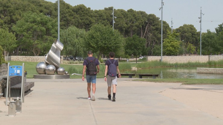 Dos jóvenes pasean por el parque de la Universidad, en Huesca.
