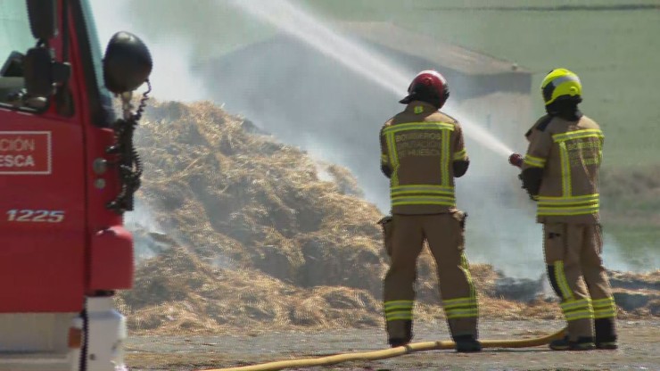 Bomberos de Huesca tratan de sofocar el incendio en un almacén de Lanaja.