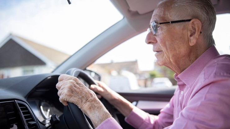 Una persona mayor al volante de un coche. / Canva