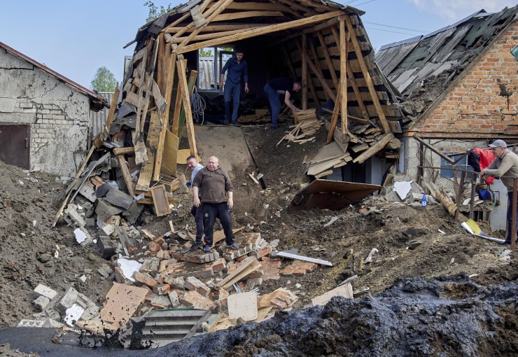 Varios vecinos retiran escombros tras un ataque con cohetes en el asentamiento de Zolochiv, en la zona de Járkov (Ucrania), el 14 de mayo de 2023, en medio de la invasión rusa. / EFE.