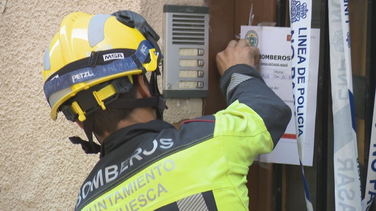 Un bombero pega un cartel en el edificio desalojado en Huesca.