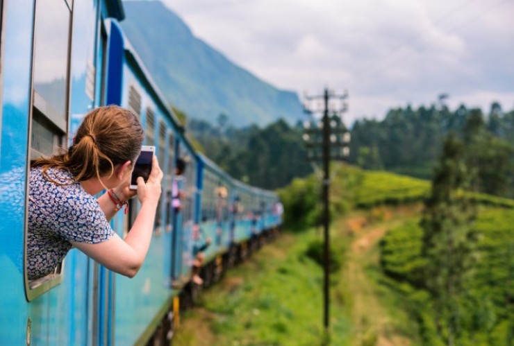 Una joven tomando una foto desde un tren. / Canva.