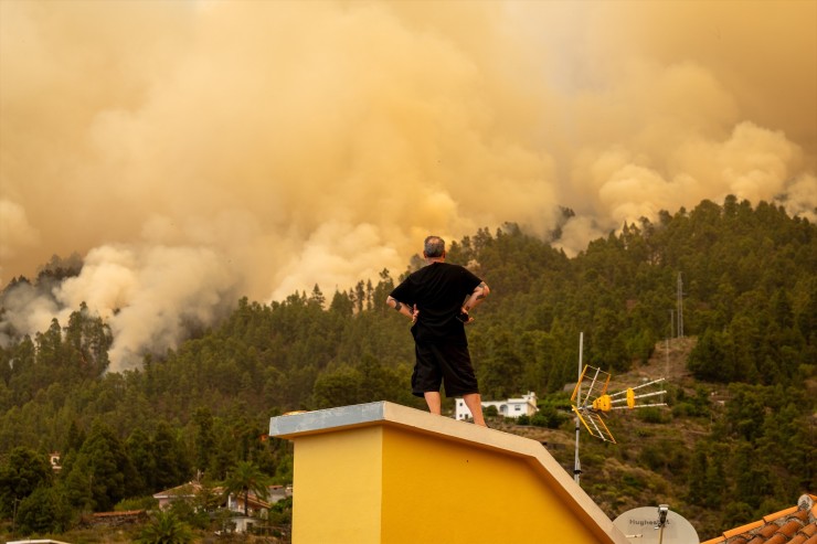 Un vecino observa desde el tejado de una casa el incendio forestal declarado en la Palma. / Europa Press.