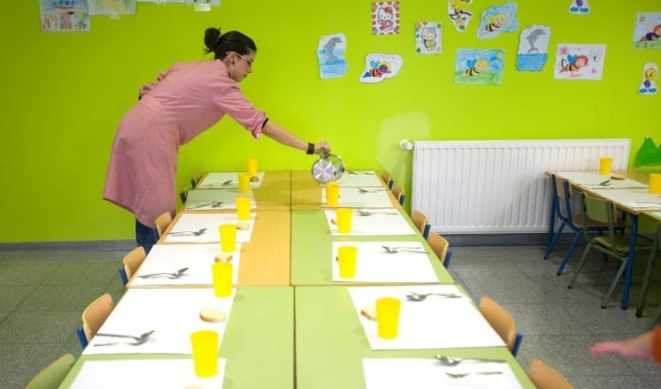 Una cuidadora del comedor escolar prepara la mesa para los alumnos. / Europa Press