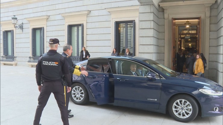 Un policía delante de un coche oficial a las puertas del Congreso.