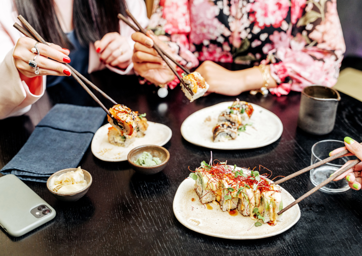 Tres personas comen sushi. / Canva