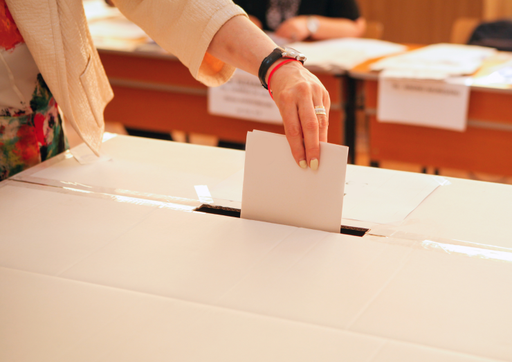 Una mujer deposita su voto en una urna. / Canva