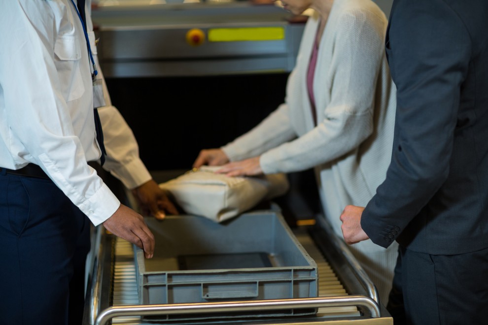 Una pasajera recoge sus pertenencias de la bandeja tras pasar un control en un aeropuerto. 