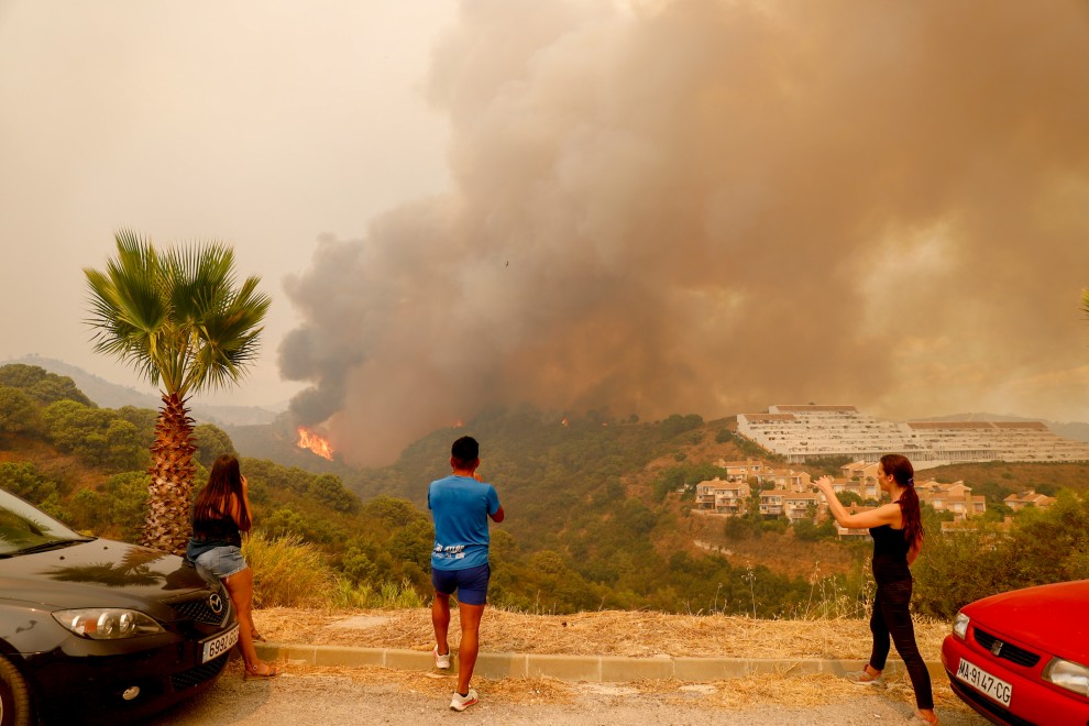 Varios jóvenes recogen con sus cámaras la magnitud del incendio declarado en Estepona. (EP)
