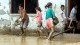 Niños de Dili intentan achicar el agua de las calles tras las lluvias torrenciales (EFE)
